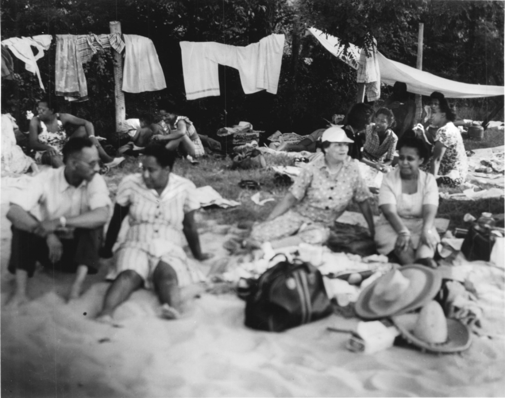 seen at Carr's Beach, people sitting in groups under clothesline.